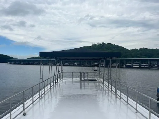 Slide: The Image of 1992 Lakeview houseboat with canopy on a calm lake, surrounded by hills and docks. - 19