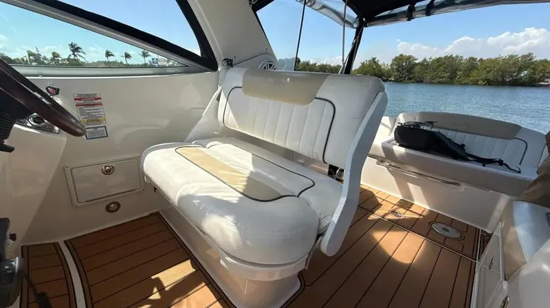 Slide: The Image of 2010 Sea Ray 310 Sundancer interior with white seating and wooden flooring, overlooking serene water. - 10