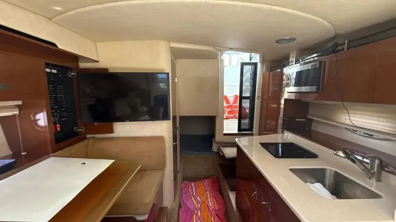 Slide: The Image of Interior of 2010 Sea Ray 310 Sundancer with kitchenette, seating, and TV. - 8