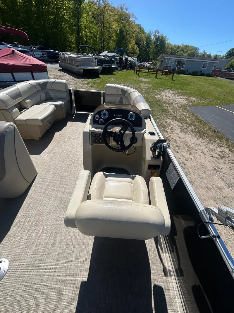 Slide: The Image of 2019 Starcraft EX 20 C pontoon boat interior with beige seating and steering console. - 7