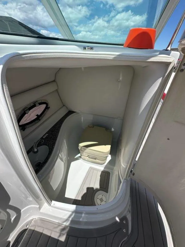 Slide: The Image of 2017 Crownline E2 boat interior with compact toilet and window, under a blue sky. - 12