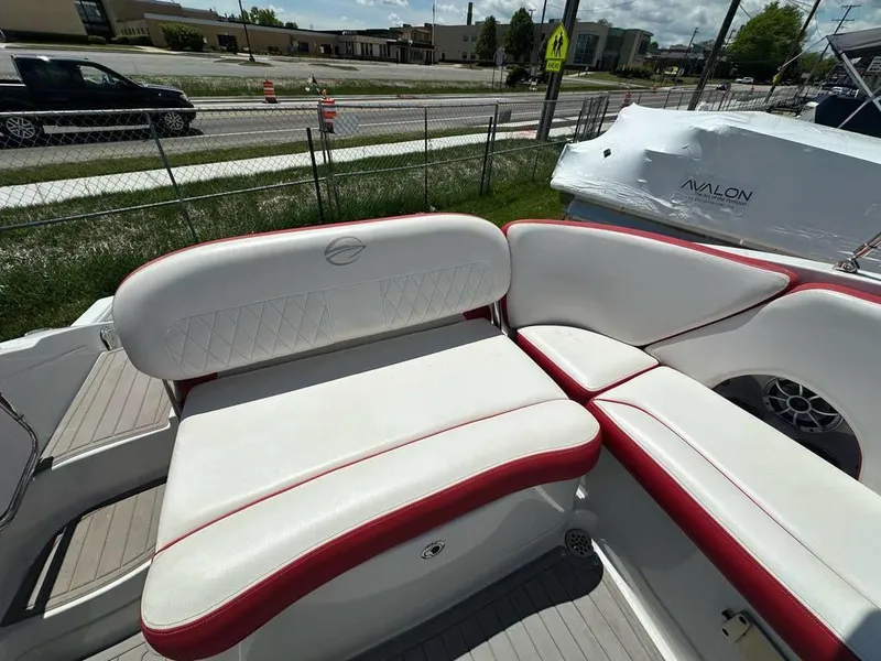 Slide: The Image of 2017 Crownline E2 boat interior with white and red seating, parked near a road. - 15
