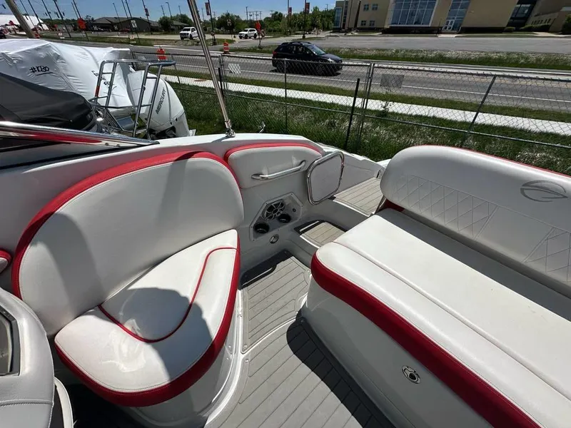 Slide: The Image of 2017 Crownline E2 boat interior with white and red seating, parked near a road. - 16