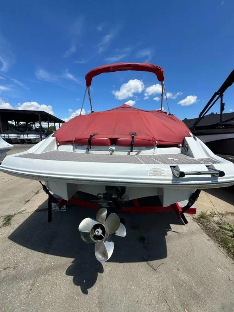 Slide: The Image of 2017 Crownline E2 boat with red cover and visible propeller, parked outdoors. - 18