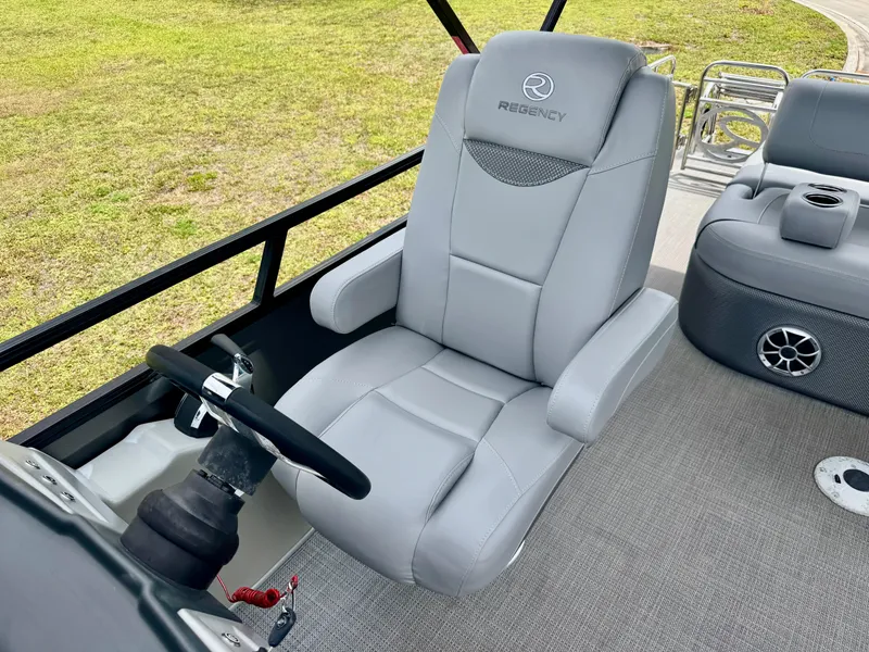 Slide: The Image of Captain's seat of 2022 Regency 230 LE3 Sport boat with steering wheel and speaker. - 13
