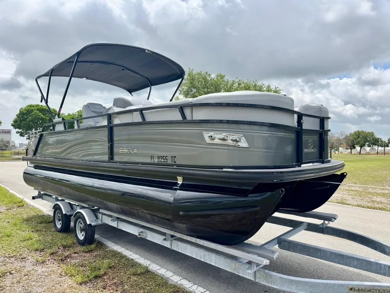 Slide: The Image of 2022 Regency 230 LE3 Sport pontoon boat on trailer under cloudy sky. - 3