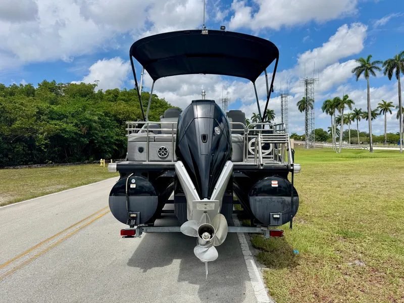 Slide: The Image of 2022 Regency 230 LE3 Sport pontoon boat on road, rear view, under blue sky. - 5