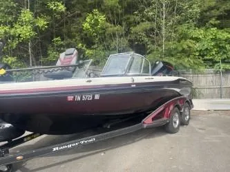 Slide: The Image of 2023 Ranger 1880MS boat on trailer, parked outdoors with trees in the background. - 0