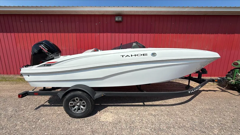 The Image of 2025 Tahoe T18 boat on trailer, parked by a red building. - 0