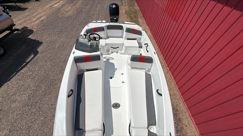 Slide: The Image of 2025 Tahoe T18 boat with spacious seating and modern design, parked beside a red wall. - 2