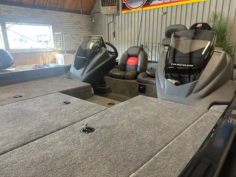 Slide: The Image of 2025 Tracker Savage 215 boat interior with dual consoles and seating in a showroom. - 11