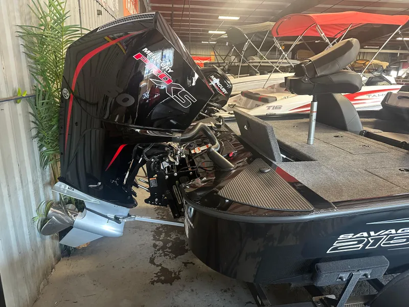 Slide: The Image of 2025 Tracker Savage 215 boat with powerful outboard motor in showroom. - 13