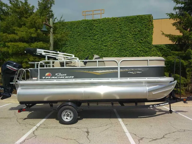 The Image of 2025 Sun Tracker Party Barge 18 DLX pontoon boat on trailer, parked outdoors. - 0