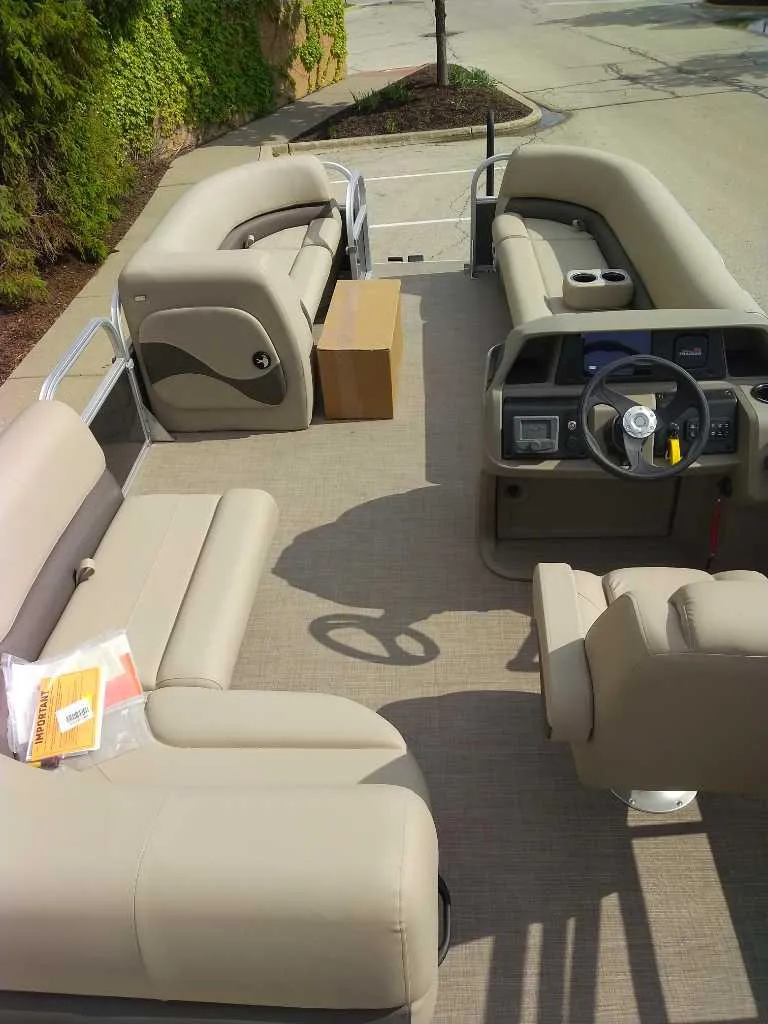 Slide: The Image of 2025 Sun Tracker Party Barge 18 DLX interior with beige seating and steering console. - 2