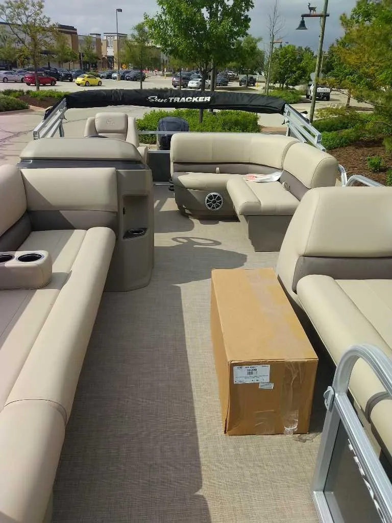 Slide: The Image of 2025 Sun Tracker Party Barge 18 DLX with beige seating and a cardboard box on deck. - 3