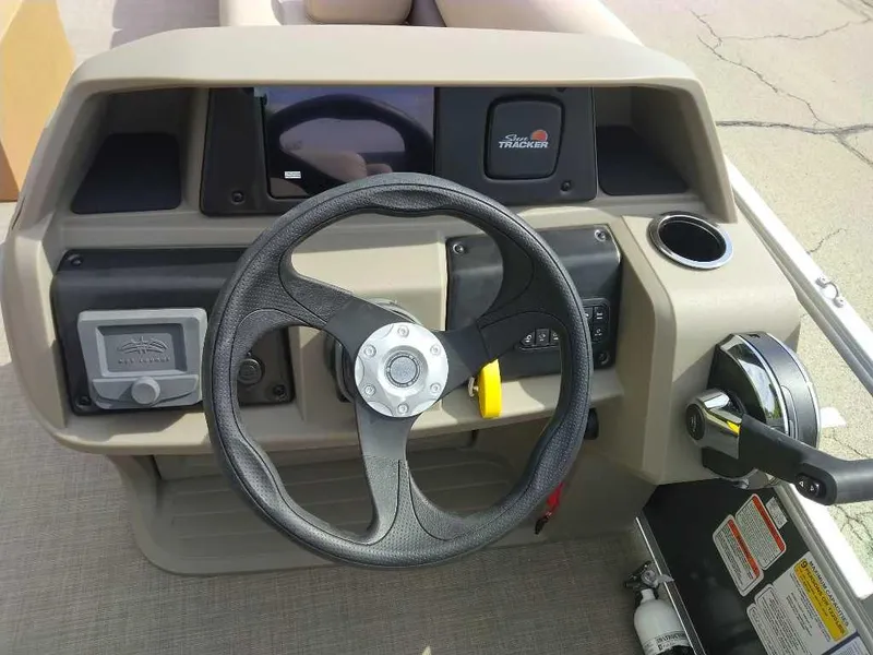 Slide: The Image of 2025 Sun Tracker Party Barge 18 DLX steering console with controls and cup holder. - 4