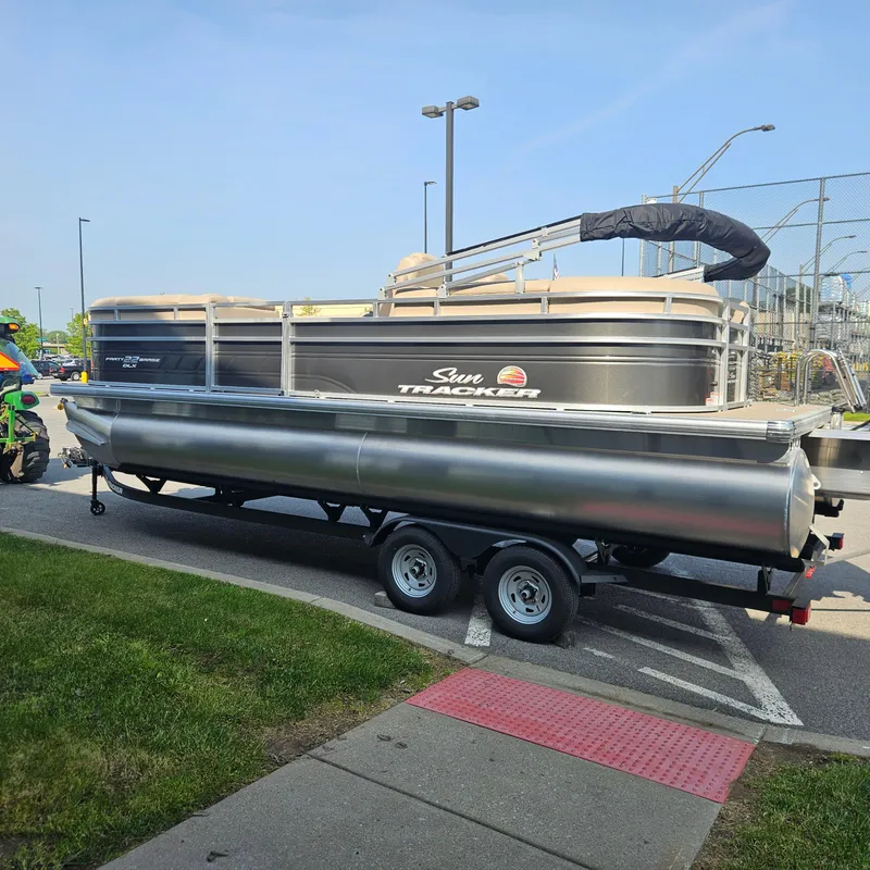 Slide: The Image of 2025 Sun Tracker Party Barge 22 DLX pontoon boat on trailer in parking lot. - 5