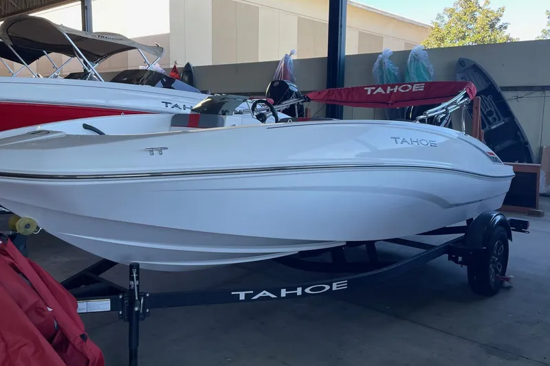 The Image of 2025 Tahoe T16 boat on trailer in showroom, sleek white design. - 0