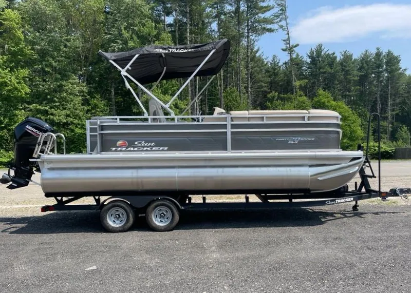 The Image of 2025 Sun Tracker Party Barge 20 DLX pontoon boat on trailer, parked outdoors. - 0