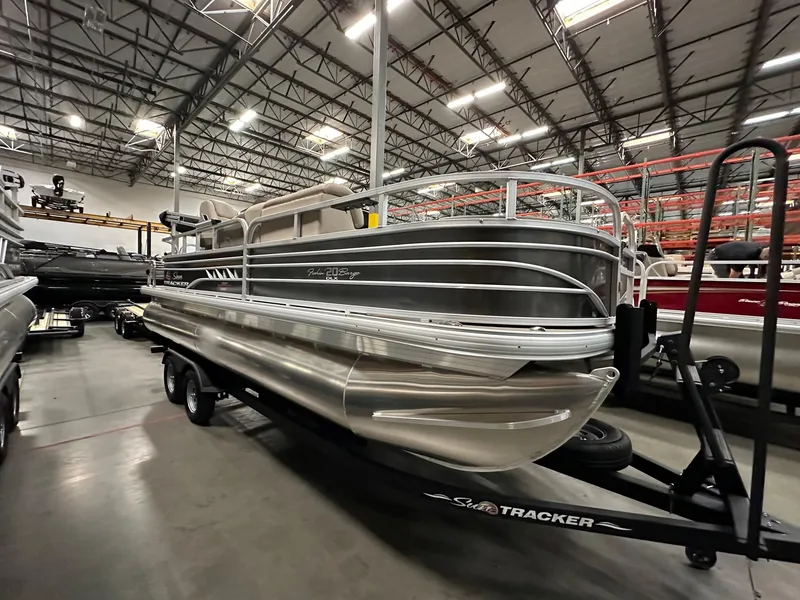 Slide: The Image of 2025 Sun Tracker Fishin' Barge 20 DLX pontoon boat in a warehouse setting. - 2
