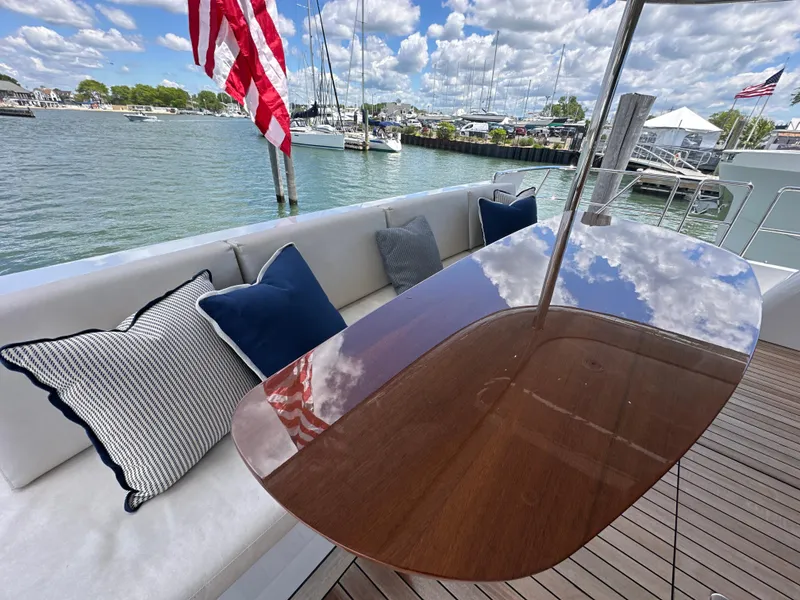 Slide: The Image of 2023 CL Yachts CLB65 yacht deck with cushions, wooden table, and American flag. - 4