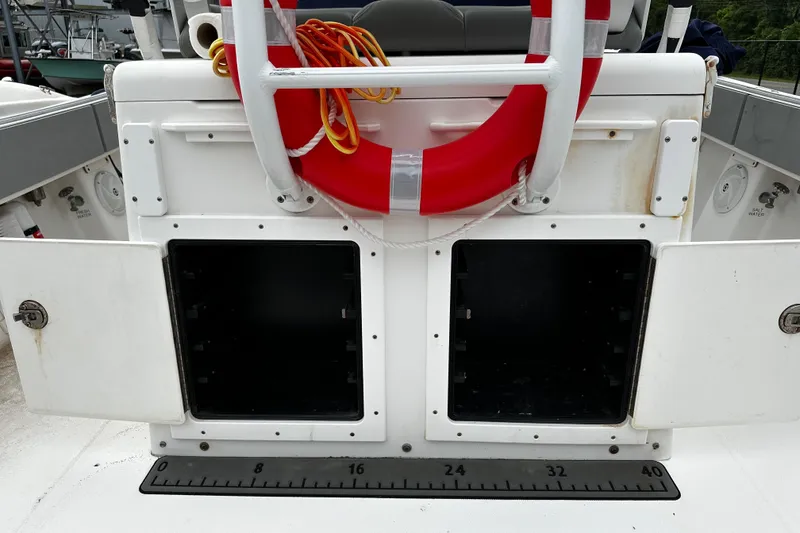 Slide: The Image of 2005 Regulator 32 FS boat storage compartments with life preserver and measuring ruler. - 12