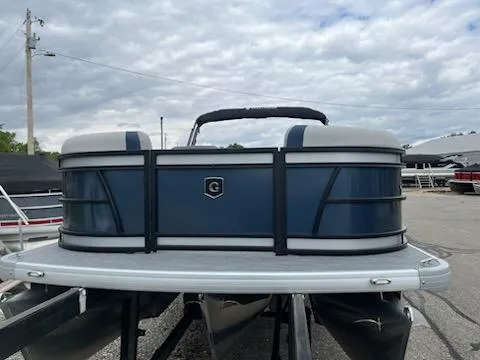 Slide: The Image of 2025 Godfrey SWEETWATER 2286SFL pontoon boat, blue and white, parked outdoors under cloudy sky. - 8