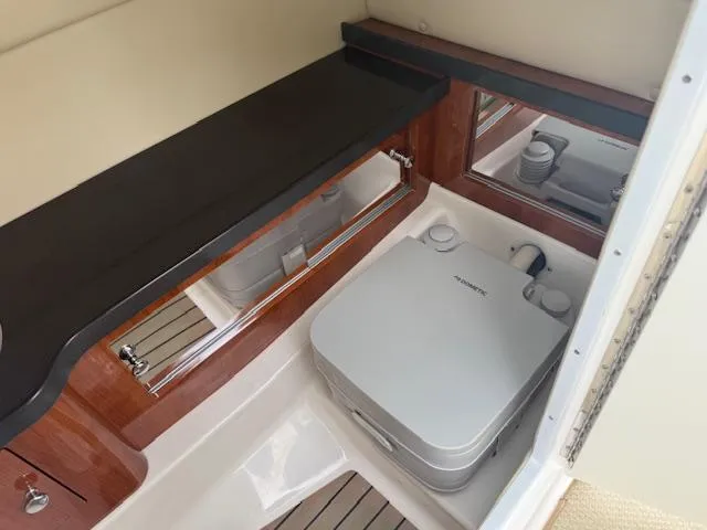 Slide: The Image of 2012 Regal 24 FasDeck boat interior with compact portable toilet and wooden accents. - 16