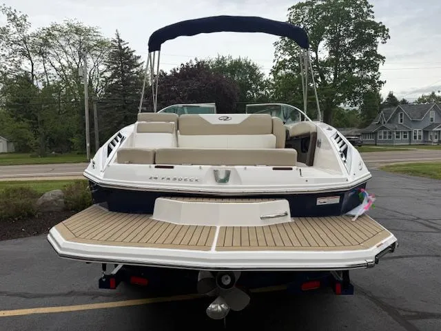 Slide: The Image of 2012 Regal 24 FasDeck boat with beige seating and swim platform, parked outdoors. - 2