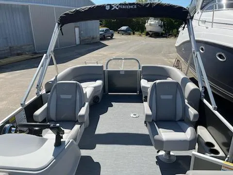 Slide: The Image of 2025 Godfrey EX2286SBCX pontoon boat with spacious seating and canopy in a marina setting. - 2