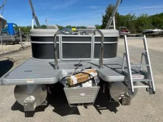Slide: The Image of 2025 Godfrey EX2286SBCX pontoon boat with ladder and rear deck, parked outdoors. - 5