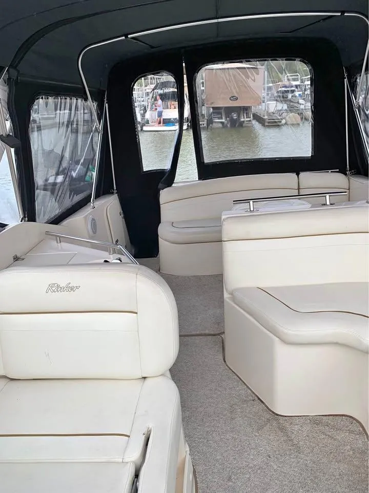Slide: The Image of 2003 Rinker 270 boat interior with white seating and marina view. - 2