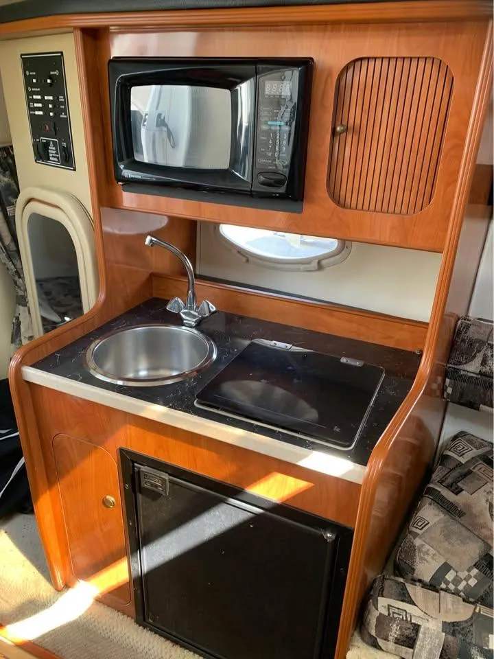 Slide: The Image of 2003 Rinker 270 boat kitchenette with sink, microwave, and mini-fridge. - 4