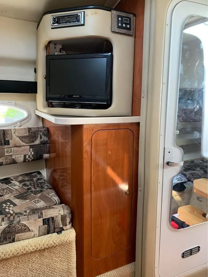 Slide: The Image of Interior of 2003 Rinker 270 boat with TV, wood cabinet, and patterned seating. - 5
