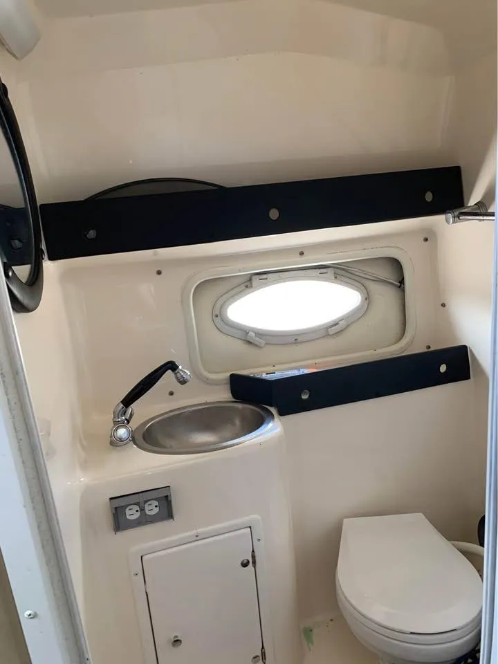 Slide: The Image of 2003 Rinker 270 boat bathroom with sink, toilet, and porthole window. - 6