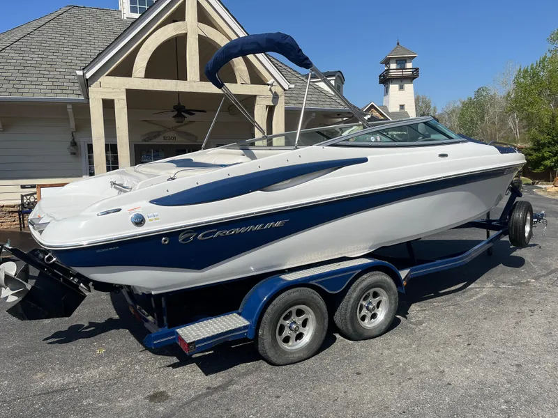 Slide: The Image of 2008 Crownline 23SS boat on trailer, parked near a house with a lighthouse in the background. - 20