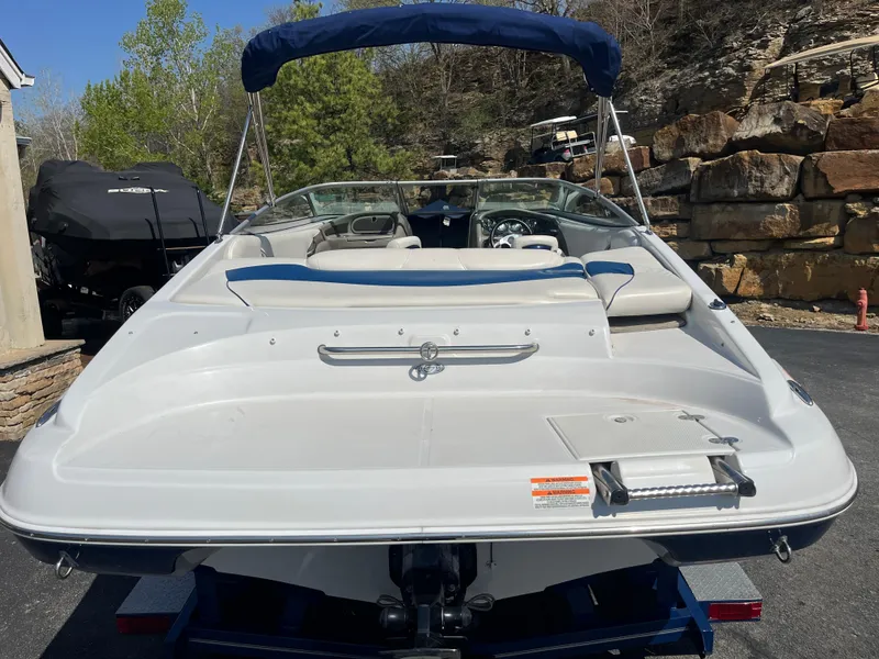 Slide: The Image of 2008 Crownline 23SS boat with blue canopy, parked on a driveway near rocky landscape. - 28