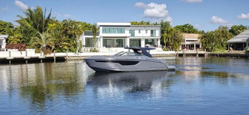Slide: The Image of 2023 Cruisers Yachts 38 GLS on serene water, modern waterfront homes in background. - 3