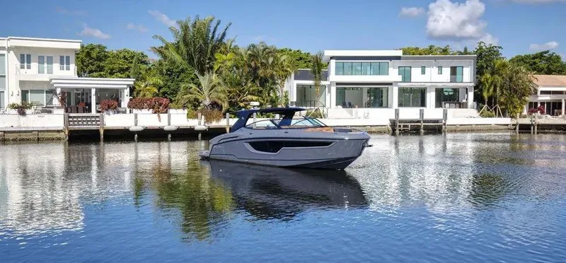 Slide: The Image of 2023 Cruisers Yachts 38 GLS on calm water near modern waterfront homes. - 4