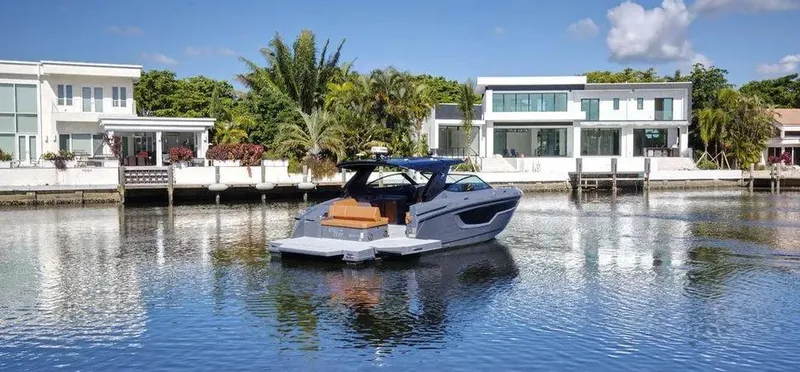 Slide: The Image of 2023 Cruisers Yachts 38 GLS on a serene waterfront with modern homes in the background. - 5