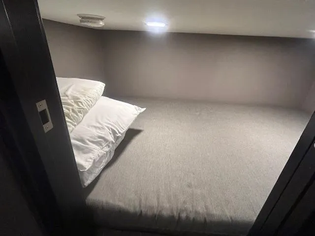 Slide: The Image of Compact sleeping area in a 2020 Adonia houseboat with pillows and soft lighting. - 15