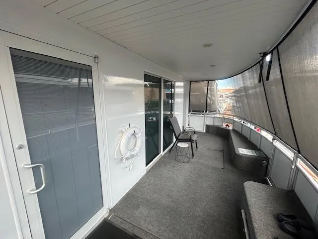 Slide: The Image of Adonia 2020 houseboat deck with seating, life preserver, and covered windows. - 3