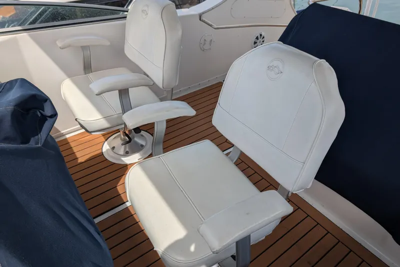 Slide: The Image of Two white captain chairs on a 2000 Bayliner 4088 boat with wooden deck. - 17