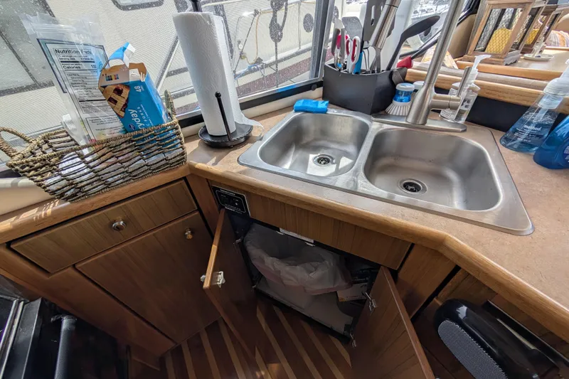 Slide: The Image of 2000 Bayliner 4088 yacht kitchen with dual sinks, wooden cabinetry, and countertop accessories. - 24