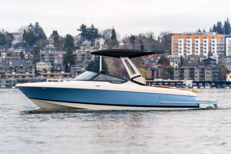 Slide: The Image of 2025 Chris-Craft Sportster 25 boat on water, urban backdrop, overcast sky. - 12