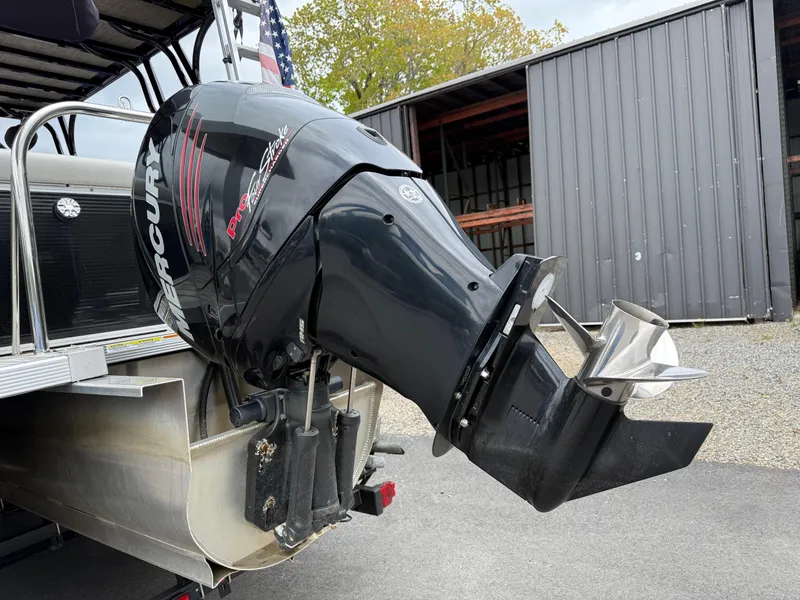 Slide: The Image of Outboard motor on a 2015 Avalon Paradise Funship 27' pontoon boat, parked near a metal building. - 13