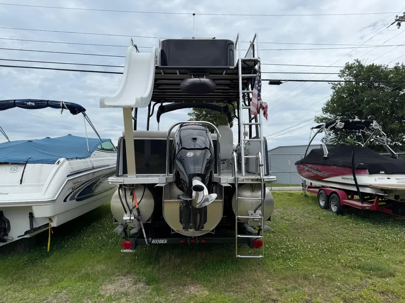 Slide: The Image of 2015 Avalon Paradise Funship 27' pontoon boat with slide and motor, parked on grass. - 16