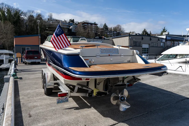 Slide: The Image of 2022 Chris-Craft Launch 27 boat on trailer, American flag, marina background. - 11
