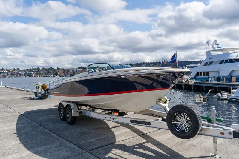 Slide: The Image of 2022 Chris-Craft Launch 27 boat on trailer by marina, under cloudy sky. - 12