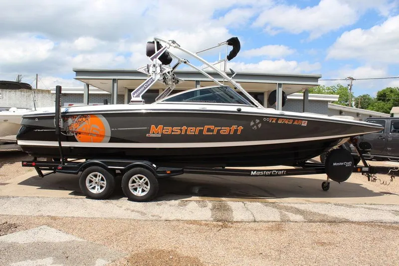 Slide: The Image of 2008 MasterCraft X45 boat on trailer, black and orange design, parked outdoors. - 3